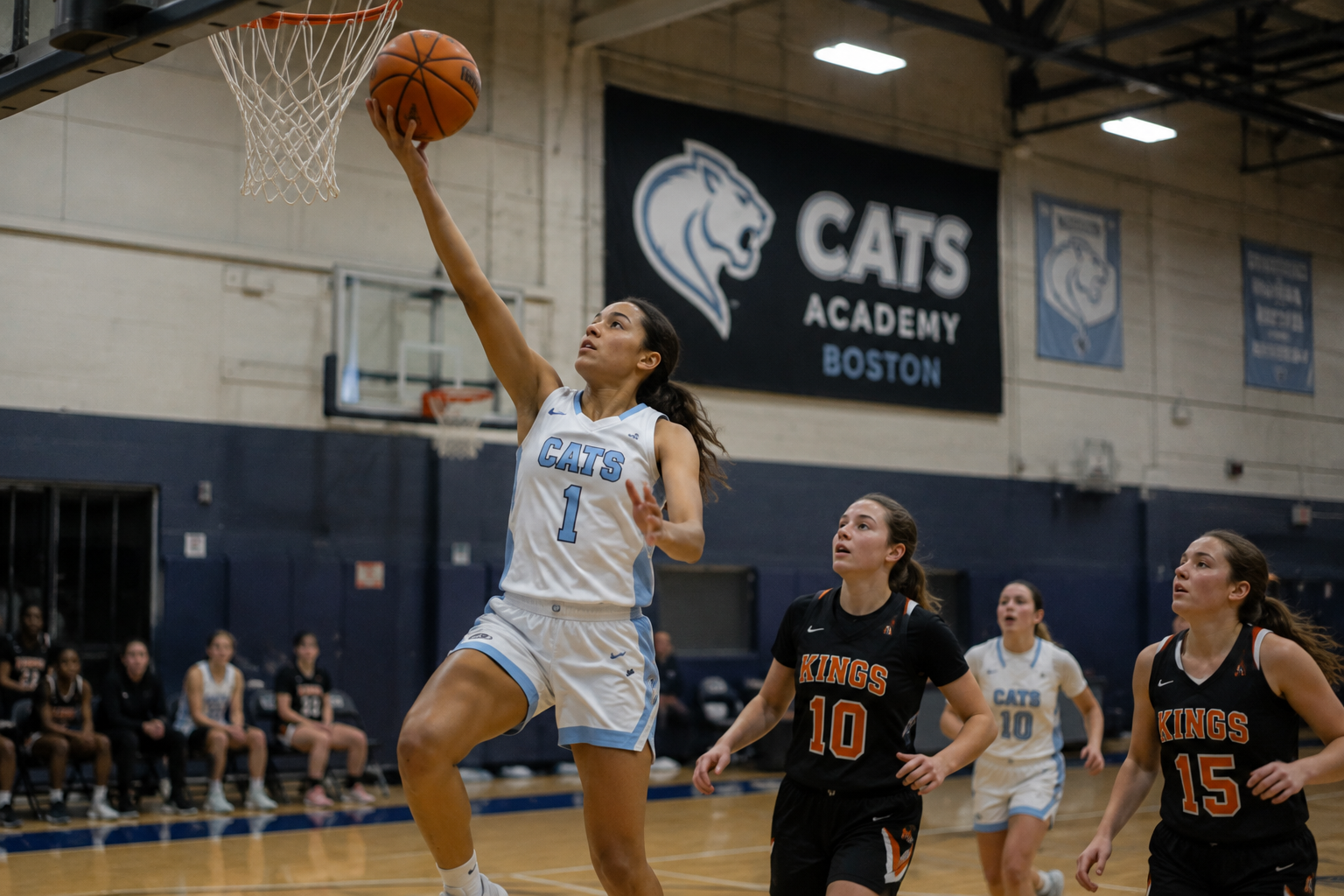 CATS Academy girls basketball player finishing a layup in a home game at CATS Academy Boston